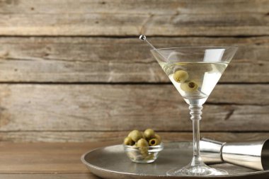 Bardakta martini kokteyli, zeytin ve tahta masada jigger, mesaj için yer.