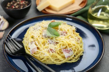 Lezzetli Carbonara makarnası ve gri desenli masada çatal bıçak takımı, yakın plan.