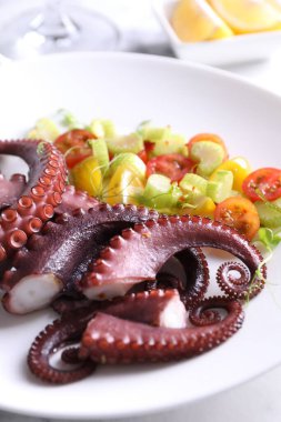 Lezzetli haşlanmış ahtapot dokunaçları ve ışık masasında salata, yakın plan.