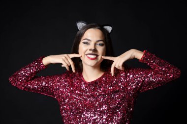 Kedi makyajı ve siyah arka planda kulakları olan çekici bir kadın.