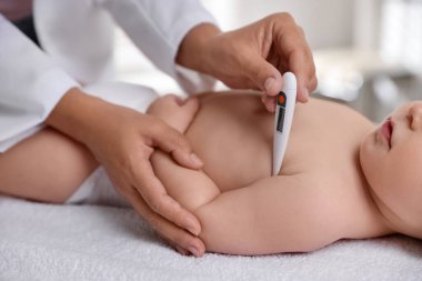 Çocuk doktoru, klinikte termometresi olan küçük çocuğu muayene ediyor. Bebeğin sağlığını kontrol ediyorum.