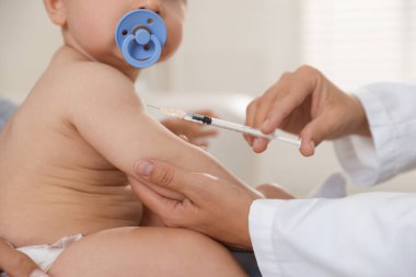 Pediyatrist klinikte bebek aşılıyor.