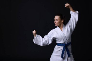 Kimonolu genç kadın siyah arka planda karate çalışıyor, mesaj için yer var.