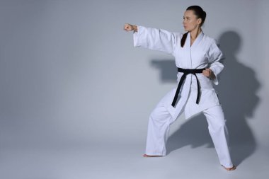 Kimonolu genç kadın gri arka planda karate çalışıyor, mesaj için yer var.