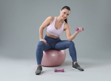 Açık gri arka planda spor yapan bir kadın spor yapıyor.
