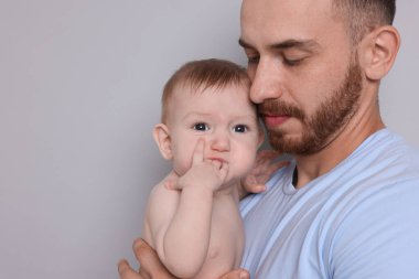 Gri arka planda sevimli bebeği olan baba, yakın plan. Metin için boşluk