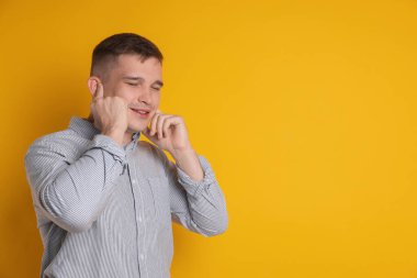 Kulaklarını turuncu arka planda parmaklarıyla kapatan adam, mesaj için boşluk