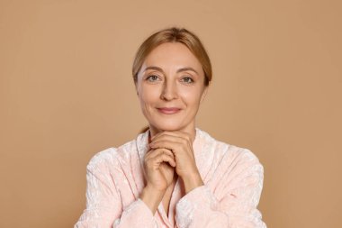 Bej arka planda sağlıklı ciltli güzel bir kadının portresi.
