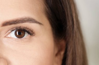 Açık arka planda güzel uzun kirpikli bir kadın, yakın plan. Kirpik uzatma işlemi