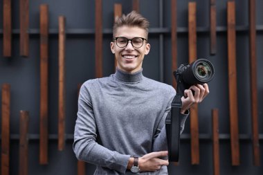 Açık havada duvarın yanında modern kamerası olan profesyonel fotoğrafçı.
