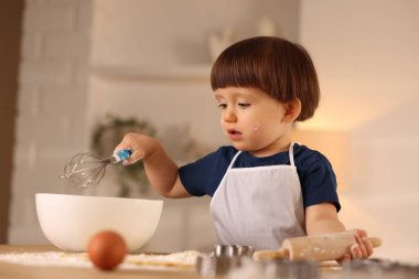 Şirin küçük çocuk içeride hamur yapıyor.