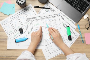 Kağıt üzerinde kablo çerçevesi oluşturan web sitesi tasarımcısı ahşap masa, üst görünüm kalem