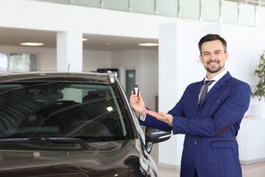 Kuaförde yeni siyah arabanın yanında anahtarı tutan mutlu bir satıcı.