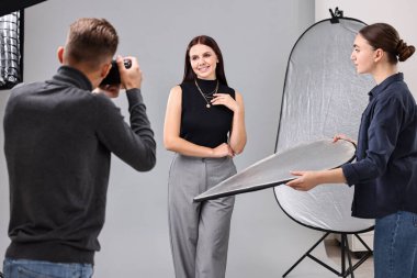 Profesyonel fotoğraf stüdyosunda modelle çalışan fotoğrafçı ve asistan.