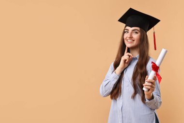 Mezuniyetten sonra bej arka planda diplomalı mutlu bir öğrenci. Metin için boşluk