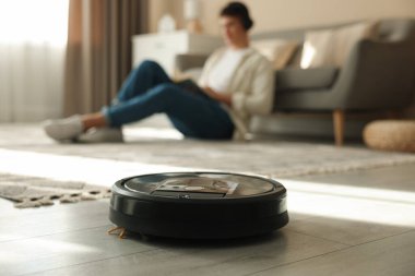 Robotik süpürge zemini temizlerken erkekler evde rahatlarken, seçici odaklanma