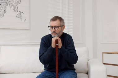 Evde bastonu olan olgun bir adam.