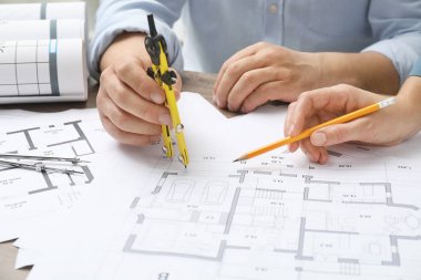 Projeyle çalışan mimarlar, yakın plan. Ahşap masaya farklı teknik çizimler.