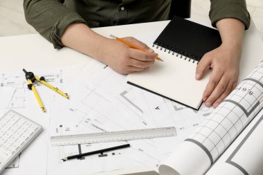 Projeyle çalışan mimar, yakın plan. Beyaz masadaki farklı teknik çizimler