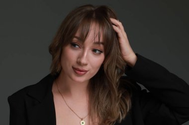 Gri arka planda şık saç kesimi olan çekici bir kadın.