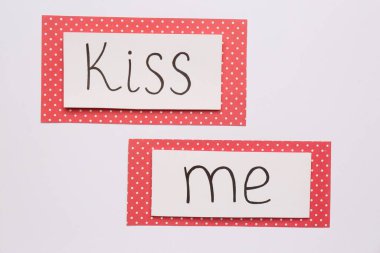 Cards with phrase Kiss me on white background, top view clipart