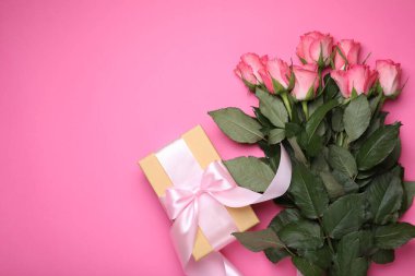 Hediye kutusu ve pembe arka planda güzel çiçekler. Metin için boşluk