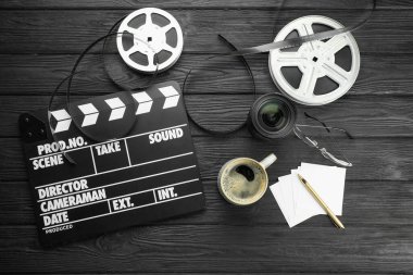 Film alkışı, film makaraları ve kamera lensleri siyah ahşap masada, düz yatıyordu.