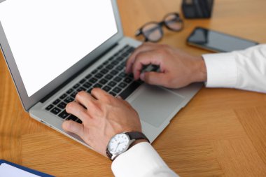 Ahşap masada dizüstü bilgisayarda yazan ofis çalışanı, yakın plan.
