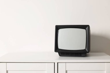 Beyaz duvara karşı göğüs çekmeceleri üzerinde Retro TV. Metin için boşluk