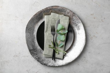 Güzel tabaklar, çatal bıçak takımı, peçete ve okaliptüs dalı gri desenli masa, üst manzara