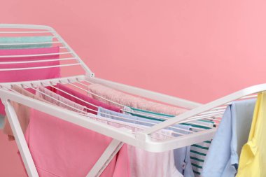 Açık pembe arka planda temiz çamaşırları olan kuru askı, yakın plan.