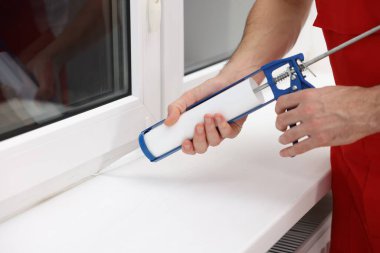 Caulking gun ile çalışan işçiler pencereyi içeriden kapatıyor.
