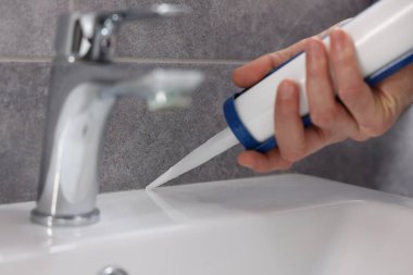 Banyodaki lavaboyu kazıyan silahlı adam, yakın plan.