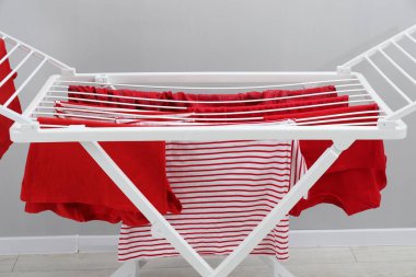 Gri duvarın yanında temiz çamaşırları olan kuru askı, yakın plan.