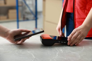 Kapalı mekândaki masada akıllı telefondan servis yapan kadın, yakın plan.