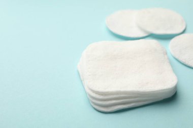 Açık mavi arka planda temiz pamuk pedler, yakın plan. Metin için boşluk