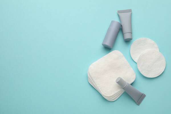 Чистые хлопковые подушечки и косметические средства на светло-голубом фоне, плоская раскладка. Пространство для текста