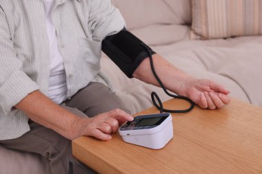 Üst düzey kadın, ahşap masada kan basıncını ölçüyor, yakın plan.