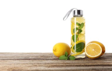 Şişe içinde naneli limon suyu ve beyaz arka planda tahta masada taze meyveler. Metin için boşluk