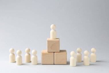 Rekabet konsepti. Ahşap küplerdeki insan figürü ve ışık arka planındaki diğer figürler