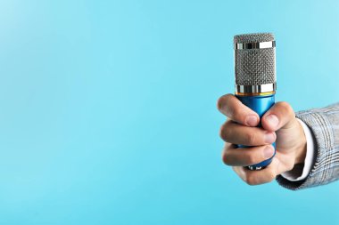 Açık mavi arka planda mikrofonu olan adam, yakın plan. Metin için boşluk