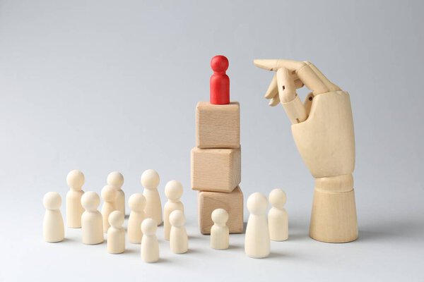 Конкурс концепции. Человеческая фигура на деревянных кубиках, другие сзади и ручная модель на светлом фоне