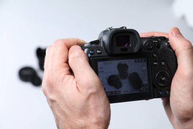 Fotoğrafçı beyaz arka planda profesyonel kamerayla fotoğraf çekiyor, yakın plan.