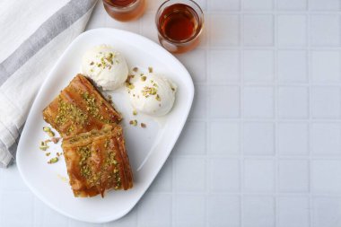Beyaz fayanslı masada servis edilen ezilmiş fındıklı ve dondurmalı enfes baklava. Metin için boşluk