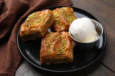 Ahşap masada ezilmiş fındıklı ve dondurmalı enfes baklava, yakın plan.