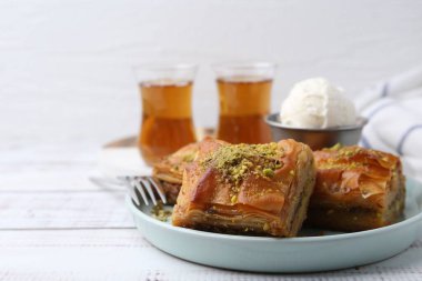 Beyaz ahşap masada ezilmiş fındıklı ve dondurmalı enfes baklava, yakın plan. Metin için boşluk