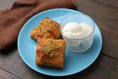 Lezzetli baklava, doğranmış fındık ve bir kepçe dondurma, ahşap masa, yakın plan.