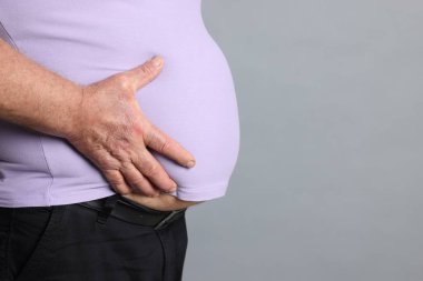 Gri arka planda dar tişörtlü şişman bir adam, yakın plan. Metin için boşluk