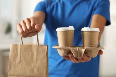 Kese kağıdı ve bardaklı fast-food işçisi, yakın plan.