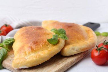 Beyaz masada fesleğen ve domatesli lezzetli vejetaryen calzones, yakın plan.